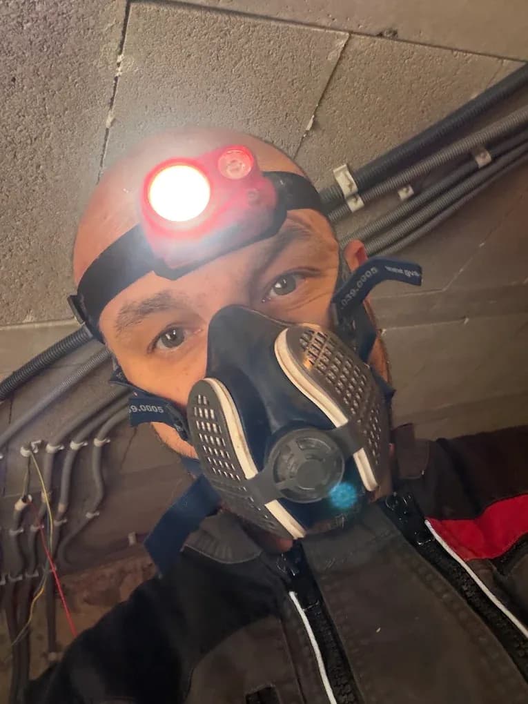 Bartlomiej Lisiewicz porte un masque de protection respiratoire et une lampe frontale dans un espace confiné